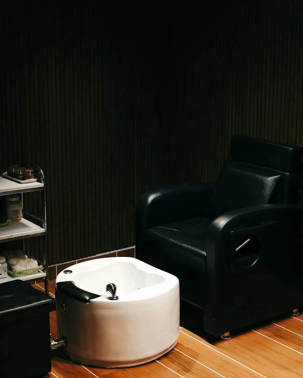 Black leather pedicure chair beside a white foot spa